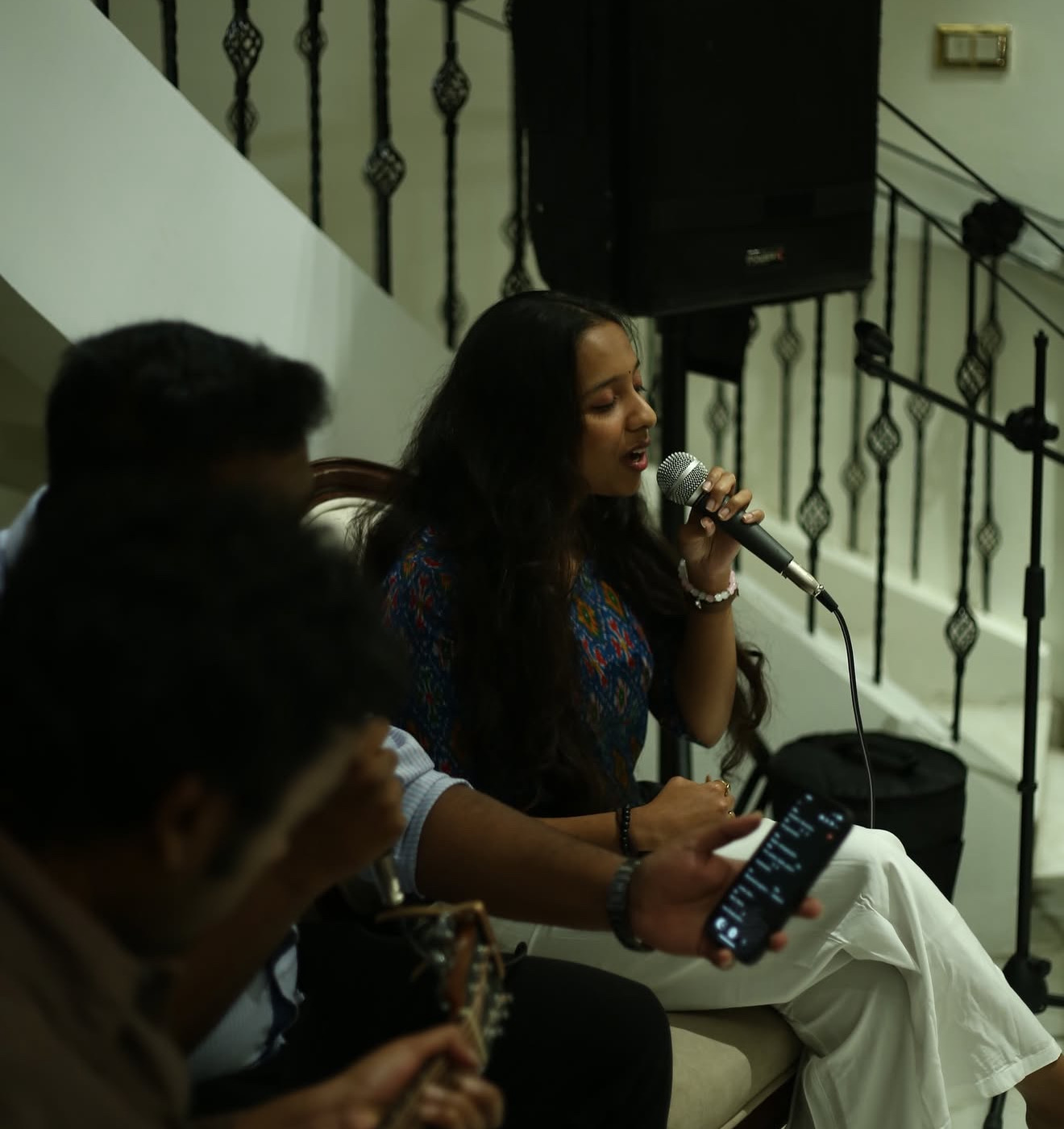 A singer performing with lyrics on a phone screen nearby